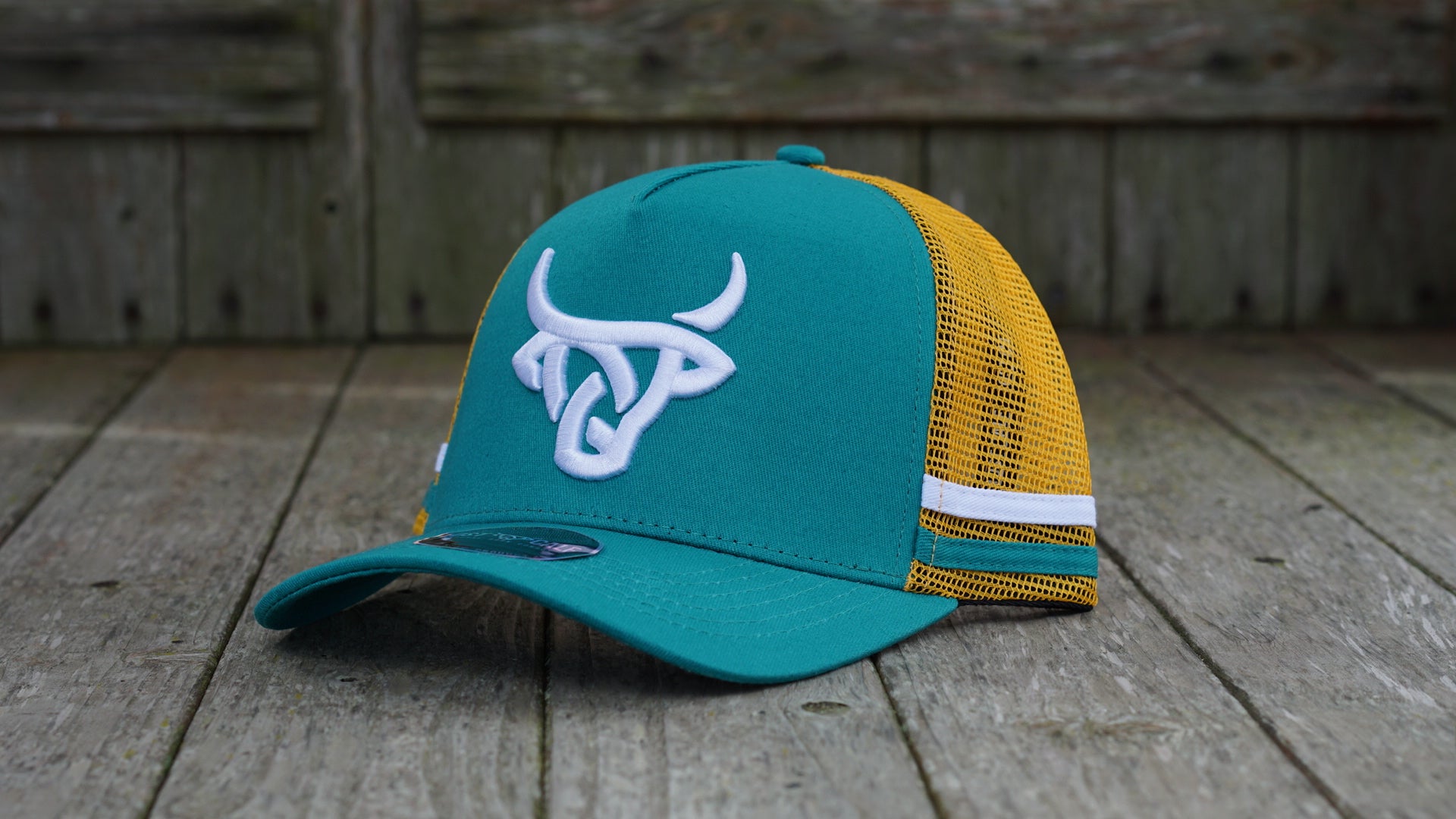 A teal and yellow baseball cap with a Lost Calf logo embroidered on the front, and a yellow mesh back. White and teal stripes across the mesh backing. 